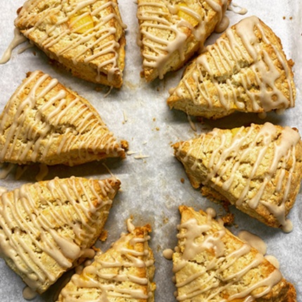 A photo of spiced peach scones cut into eight triangular pieces, drizzled with icing